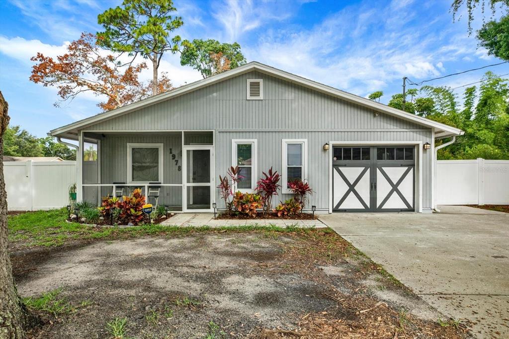 A gray house with a screened porch, a garage, and a white vinyl fence — 1978 DIX STREET, LARGO, FL