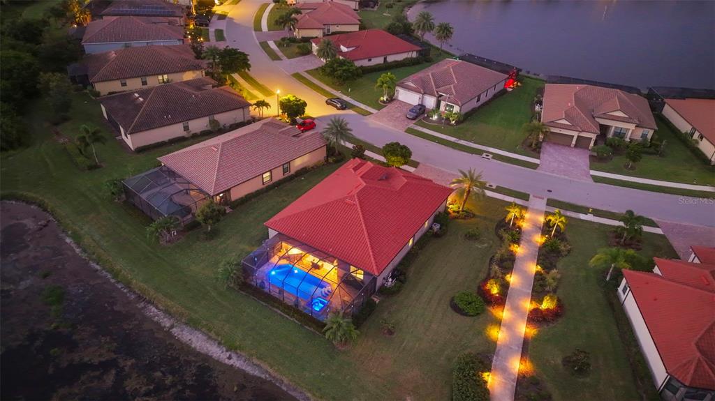 An aerial view shows a residential neighborhood with houses, swimming pools, and a lake — 20203 GRANLAGO DRIVE, VENICE, FL