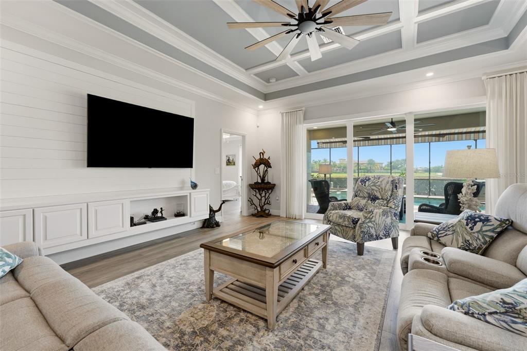 A living room features a coffered ceiling, shiplap accent wall, and sliding doors to a pool — 20203 GRANLAGO DRIVE, VENICE, FL