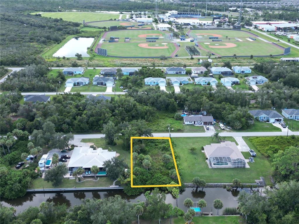 An aerial view shows a vacant, wooded residential lot situated along a canal — 2206 TEA STREET, PORT CHARLOTTE, FL