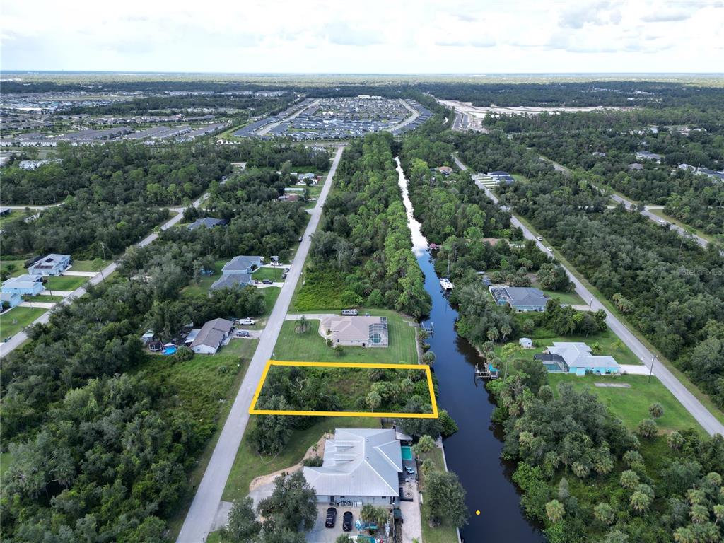 An aerial view shows a vacant, rectangular lot situated between a road and a canal — 2206 TEA STREET, PORT CHARLOTTE, FL