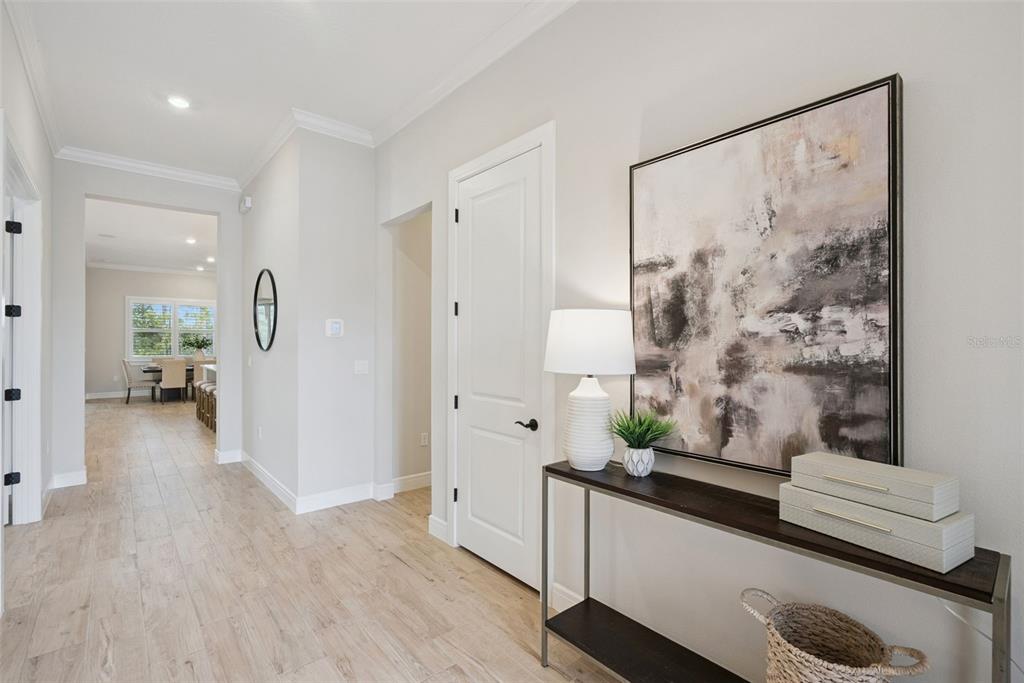 A hallway features light wood-look tile flooring, a console table with decor, and a white door — 2555 PINE PRESERVE COURT, ST CLOUD, FL