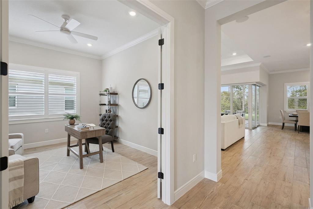 A home office with light wood floors and a desk sits beside an open living area — 2555 PINE PRESERVE COURT, ST CLOUD, FL