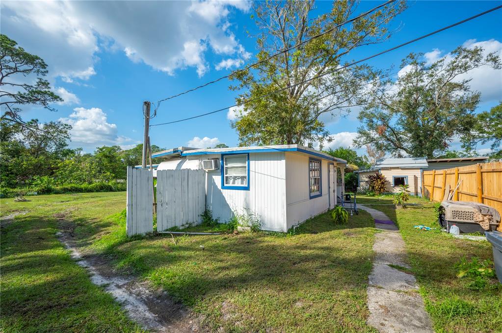 A white mobile home with blue trim sits on a grassy lot with a wooden fence — 3221 & 3225 CRUTCHFIELD ROAD, LAKELAND, FL