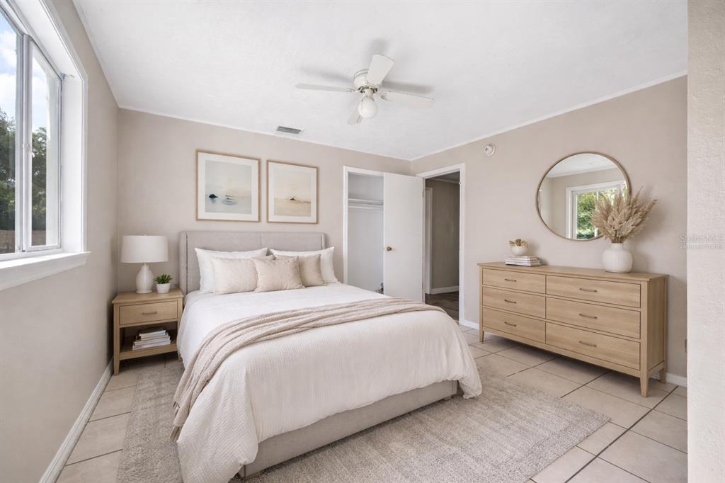 A bedroom with a bed, nightstand, dresser, round mirror, and tile flooring — 3221 & 3225 CRUTCHFIELD ROAD, LAKELAND, FL