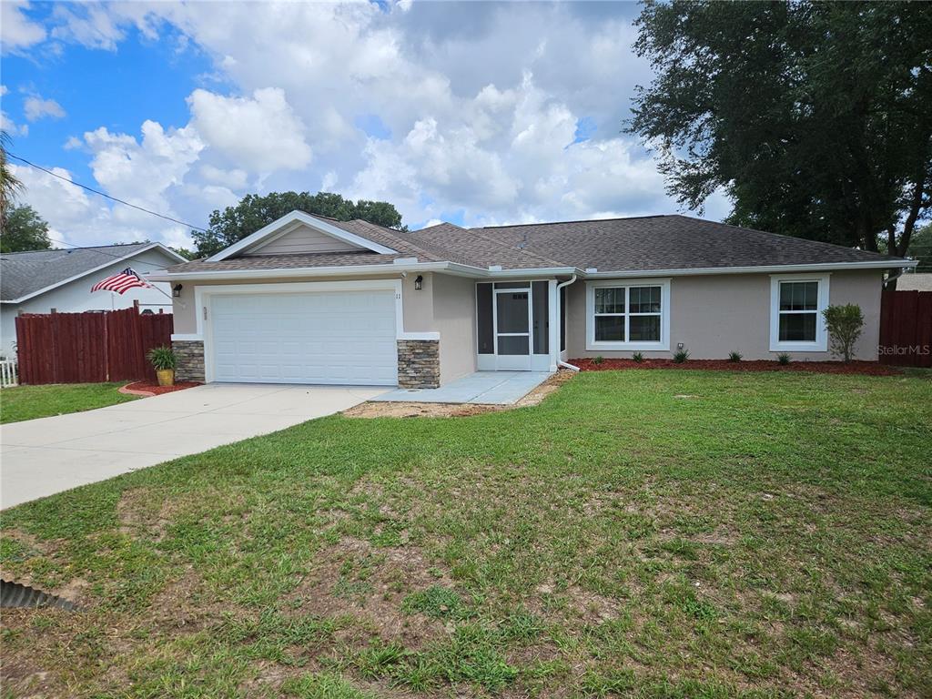 A single-story house with a two-car garage, stone accents, and a front screen door — 11 ALMOND TRAIL, OCALA, FL
