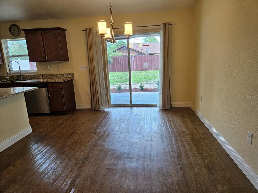 A dining area with wood-look flooring, a chandelier, and sliding glass doors leading to a yard — 11 ALMOND TRAIL, OCALA, FL