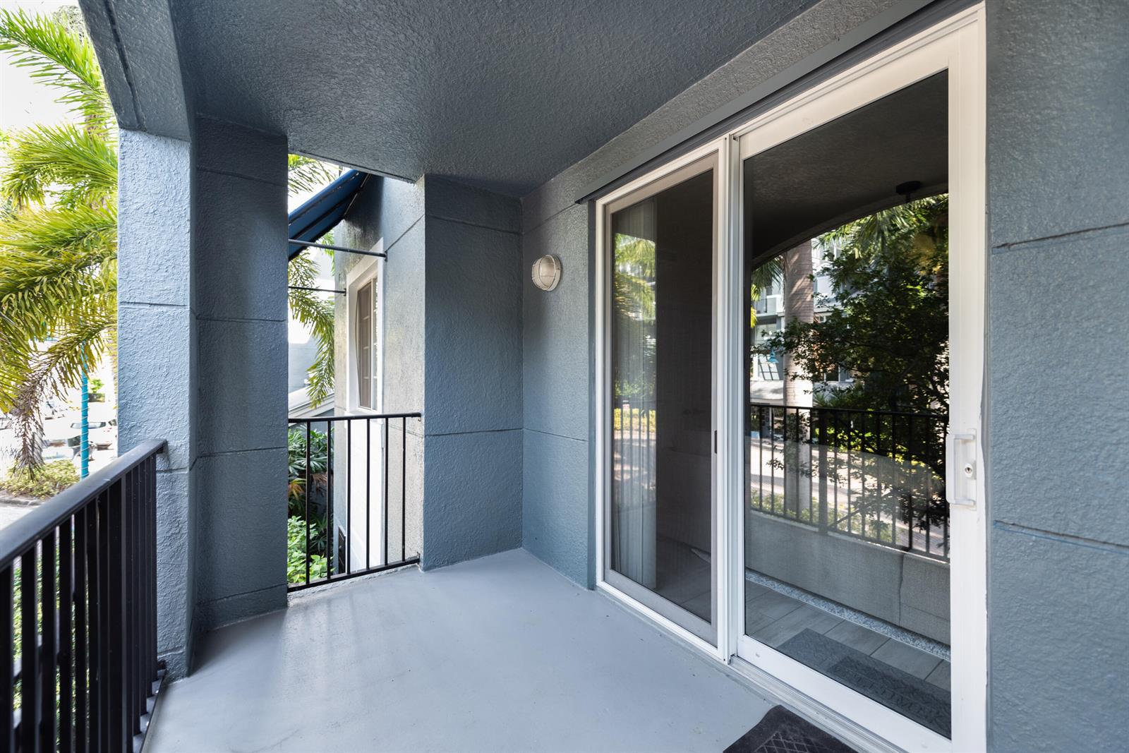 A covered balcony features gray walls, a concrete floor, and a sliding glass door — 255 NE 3rd Avenue # 2212, Delray Beach FL 33444, DELRAY BEACH, FL