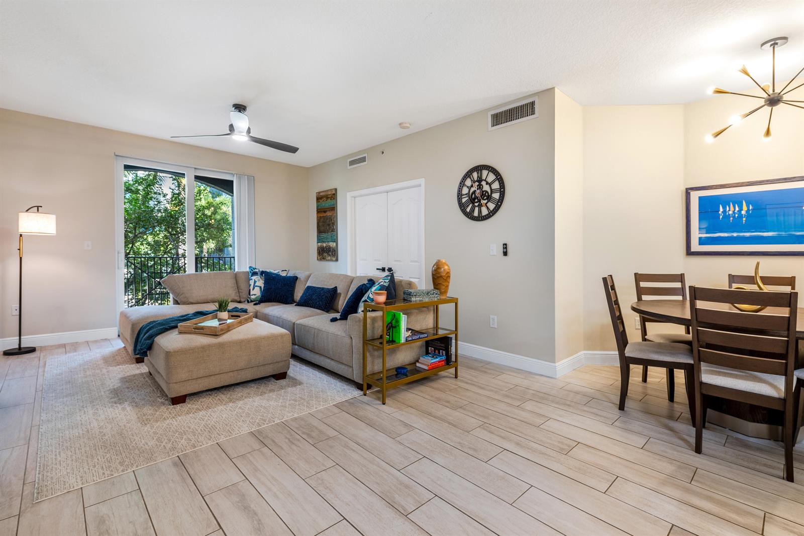 A living and dining area features a sectional sofa, tile flooring, and a modern chandelier — 255 NE 3rd Avenue # 2212, Delray Beach FL 33444, DELRAY BEACH, FL