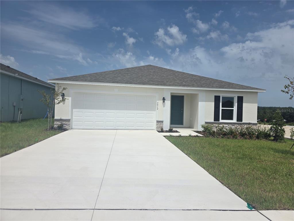 An open-concept kitchen with gray cabinets and tile flooring flows into a spacious living area — 3012 CASCADE CIRCLE, LAKE WALES, FL
