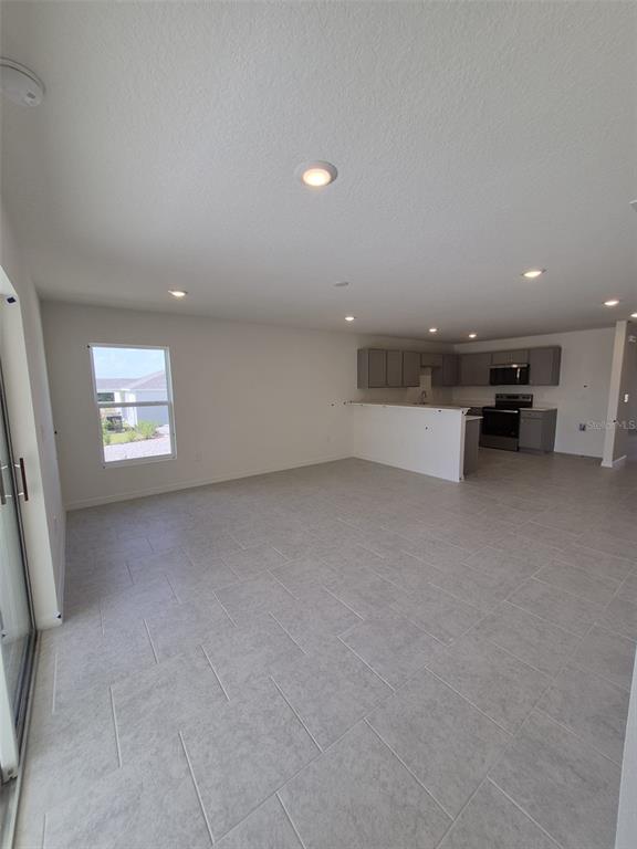 An open-concept kitchen and living area features gray tile flooring, recessed lighting, and gray cabinetry — 3012 CASCADE CIRCLE, LAKE WALES, FL