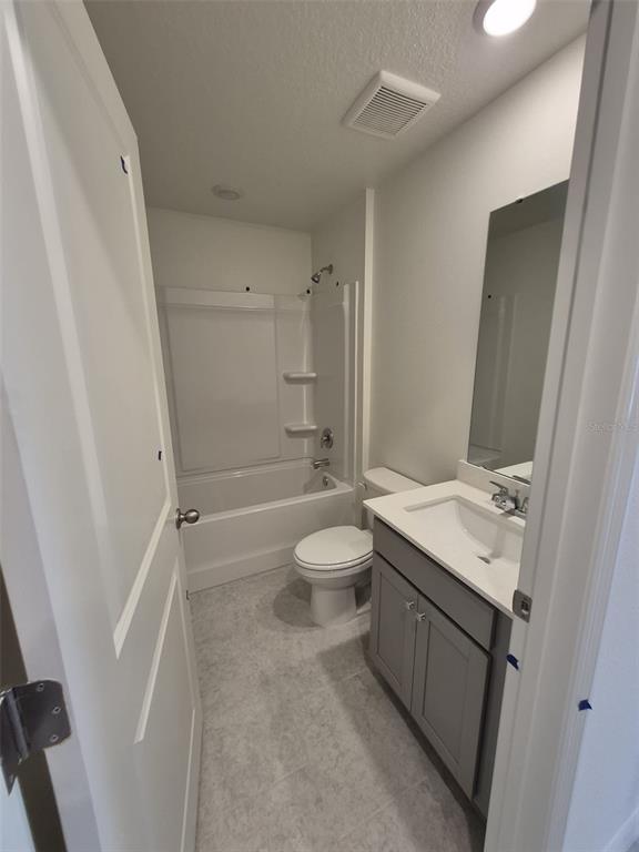 A bathroom features a gray vanity, a white toilet, and a shower-tub combination — 3012 CASCADE CIRCLE, LAKE WALES, FL