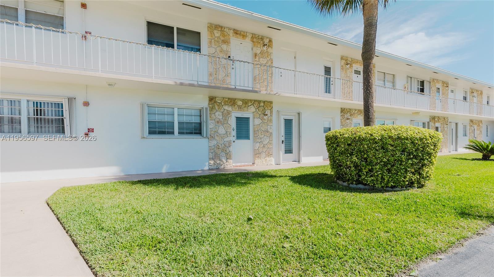 A two-story apartment building with white walls, stone accents, and a grassy front lawn — 301 S Golf Blvd # 172, Pompano Beach FL 33064, POMPANO BEACH, FL