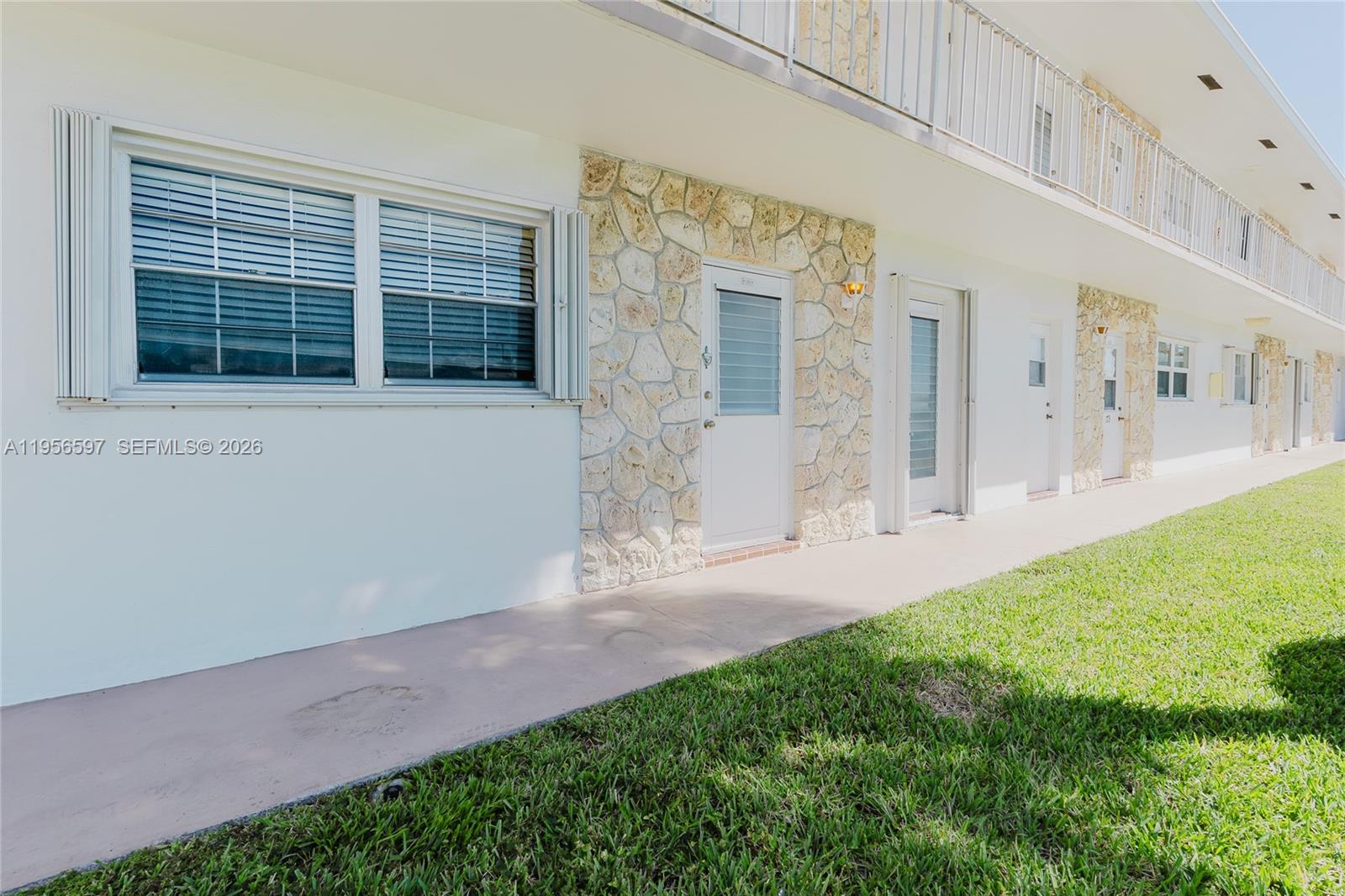The exterior of a multi-unit building features white walls, stone accents, and a concrete walkway — 301 S Golf Blvd # 172, Pompano Beach FL 33064, POMPANO BEACH, FL
