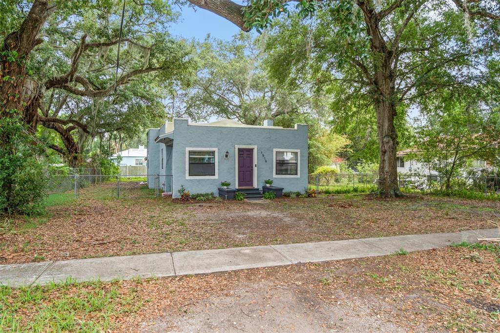 A light blue, single-story stucco house with a purple front door sits behind a yard — 1516 E ELM ROAD, LAKELAND, FL