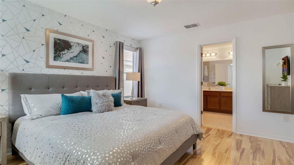 A bedroom features a gray upholstered bed, geometric wallpaper, and an attached bathroom — 430 LAS FUENTES DRIVE, KISSIMMEE, FL