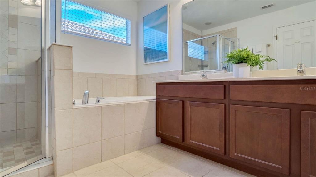 A bathroom features a soaking tub, a glass-enclosed shower, and a dark wood vanity — 430 LAS FUENTES DRIVE, KISSIMMEE, FL