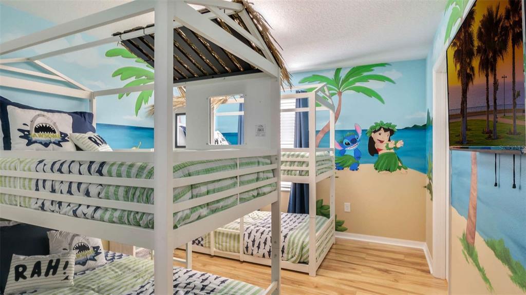 A bedroom features two white bunk beds with thatched roofs and a Lilo and Stitch mural — 430 LAS FUENTES DRIVE, KISSIMMEE, FL