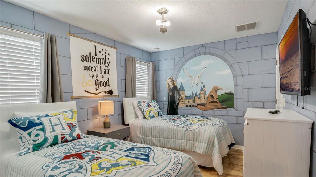 A Harry Potter-themed bedroom features two twin beds, stone-patterned walls, and a castle mural — 430 LAS FUENTES DRIVE, KISSIMMEE, FL
