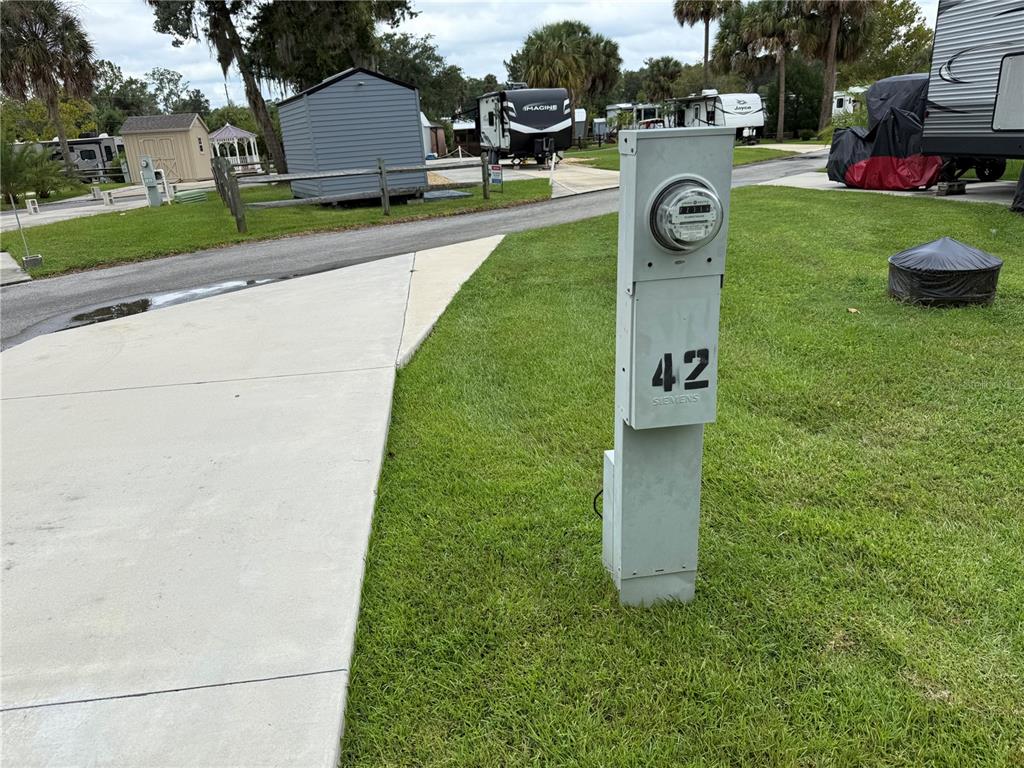 A utility pedestal with an electric meter stands on a grassy lot near a driveway — 2870 NE 103RD AVENUE, SILVER SPRINGS, FL