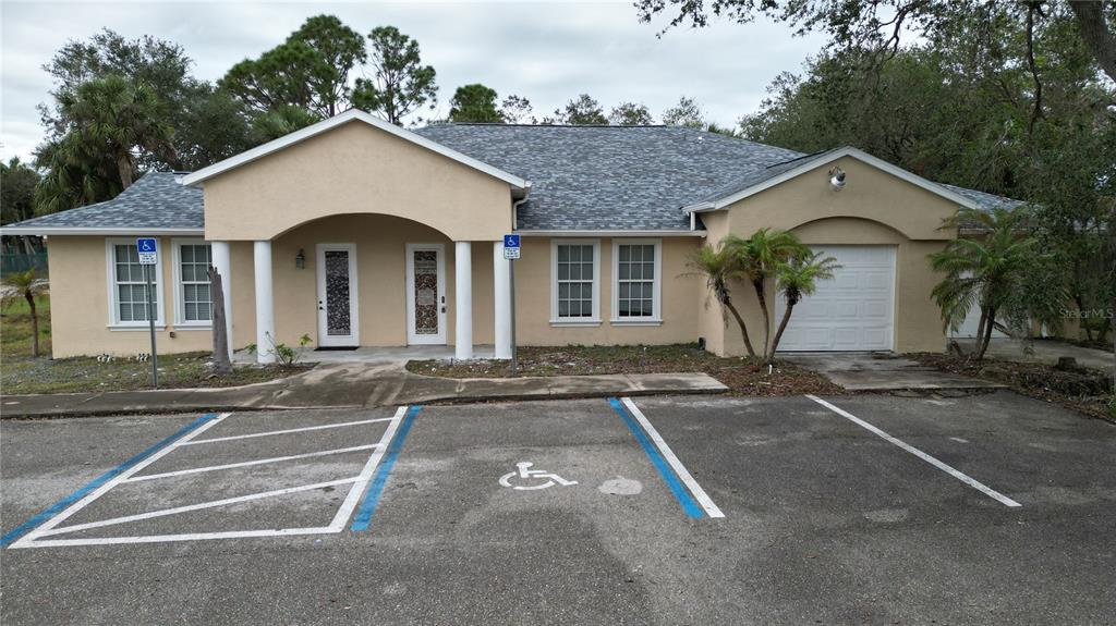 A single-story building with a beige stucco exterior, a gray shingled roof, and accessible parking — 17880 TOLEDO BLADE BOULEVARD, PORT CHARLOTTE, FL