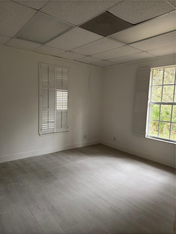 An empty room with white walls, light wood-look tile flooring, and a drop ceiling — 17880 TOLEDO BLADE BOULEVARD, PORT CHARLOTTE, FL