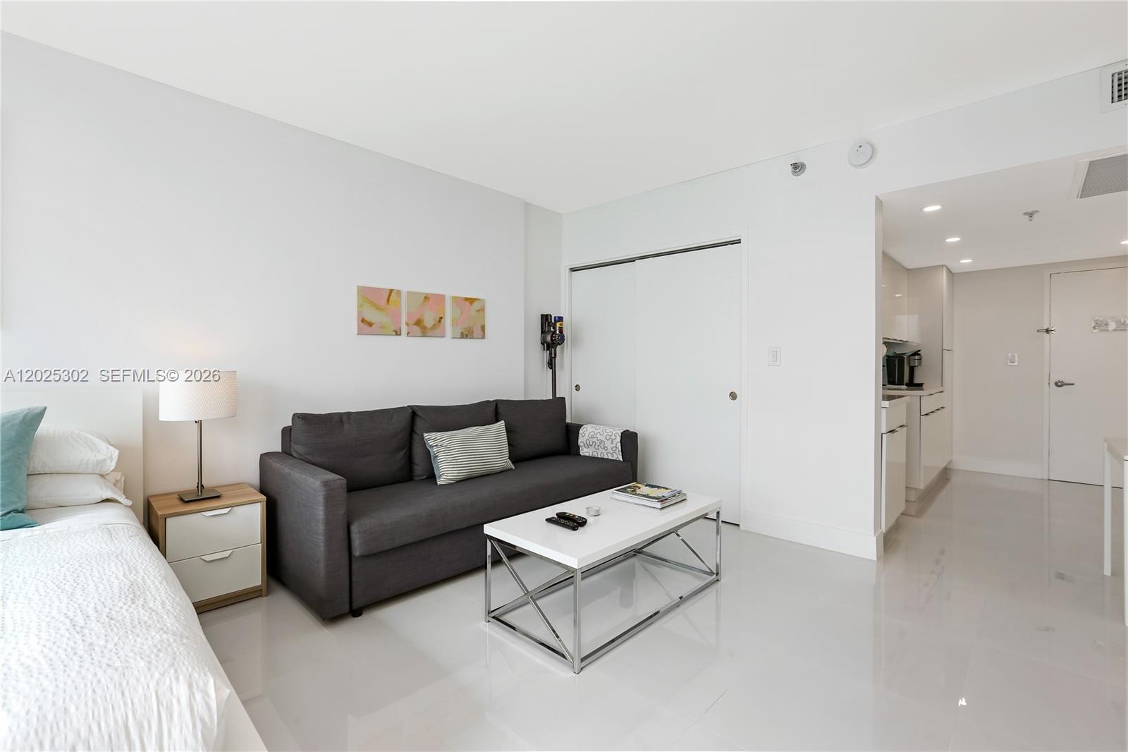 A studio apartment features a sofa, a bed, a coffee table, and an adjacent kitchen — 5445 Collins Ave # 1203, Miami Beach FL 33140, MIAMI BEACH, FL