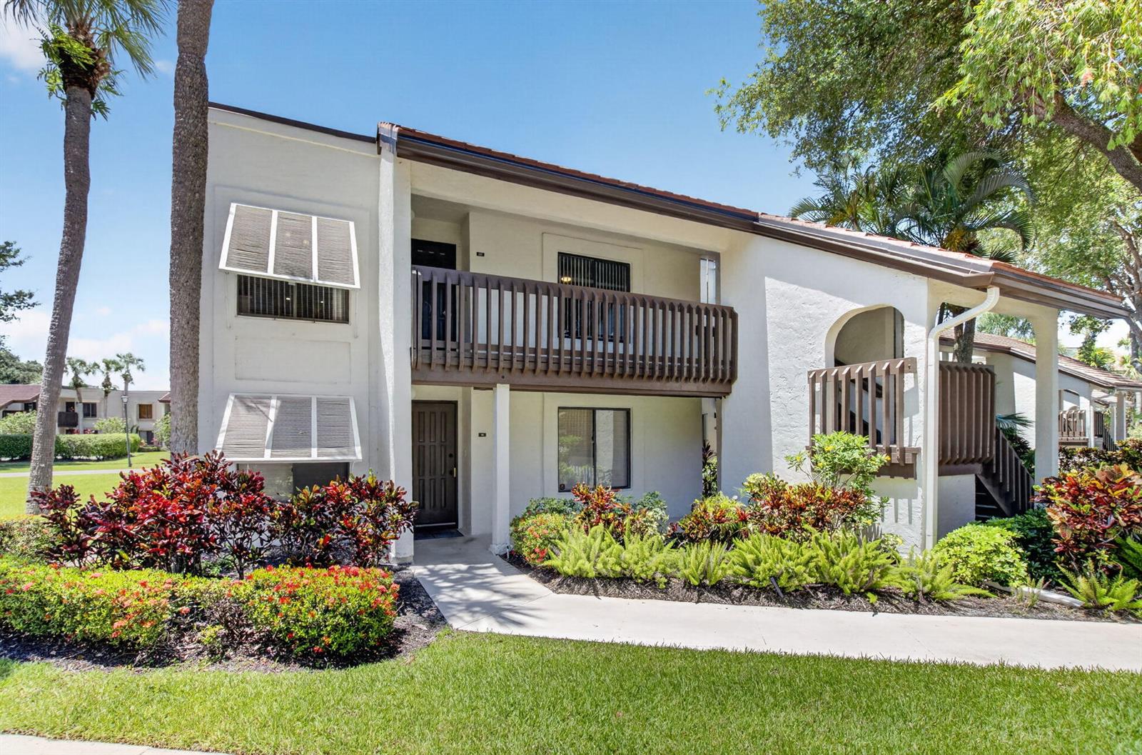 A two-story apartment building with a brown wooden balcony and white stucco exterior — 10187 Mangrove Drive # 201, Boynton Beach FL 33437, BOYNTON BEACH, FL