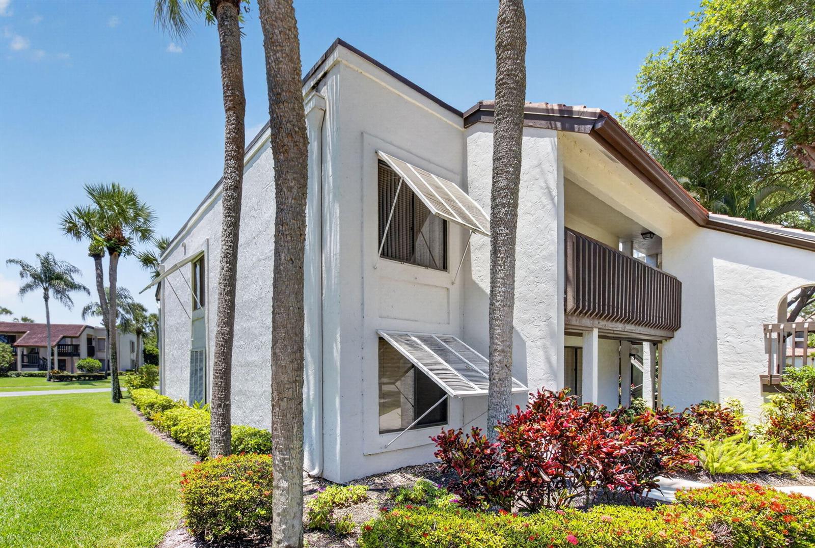 A two-story white stucco building features brown wooden balconies and white window shutters — 10187 Mangrove Drive # 201, Boynton Beach FL 33437, BOYNTON BEACH, FL