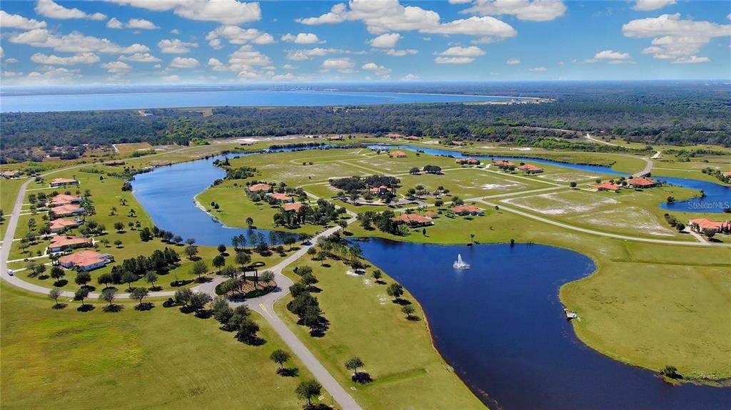 An aerial view shows a residential community with houses surrounding several ponds and green spaces — 5234 LAKE VENICE DRIVE, WIMAUMA, FL