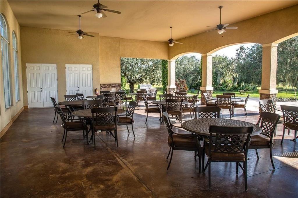 A covered outdoor patio features multiple dining tables with chairs and ceiling fans — 5234 LAKE VENICE DRIVE, WIMAUMA, FL