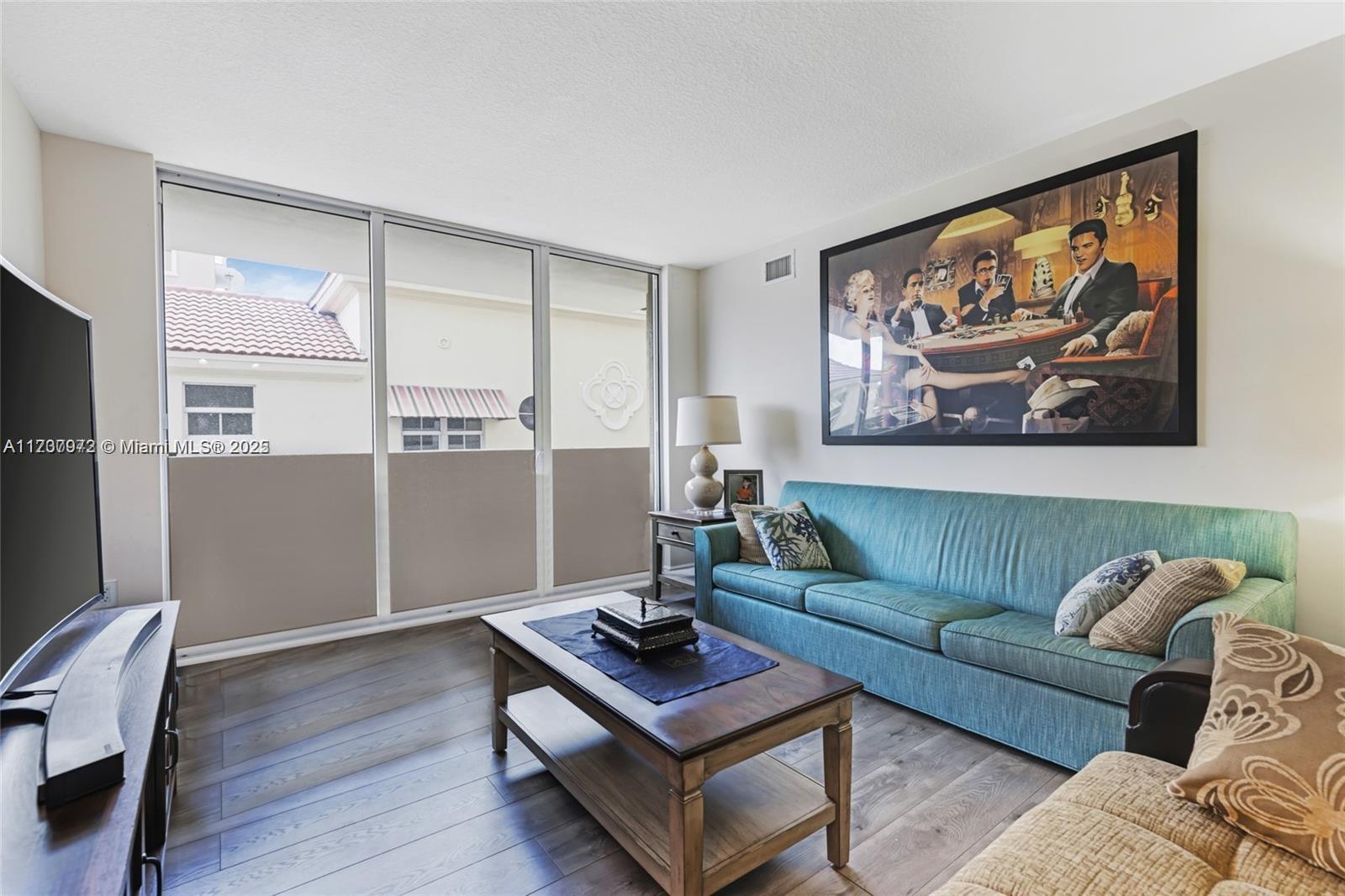 A living room features a teal sofa, a wooden coffee table, and a large wall print — 3232 SW 22nd Ter # 301, Miami FL 33145, MIAMI, FL