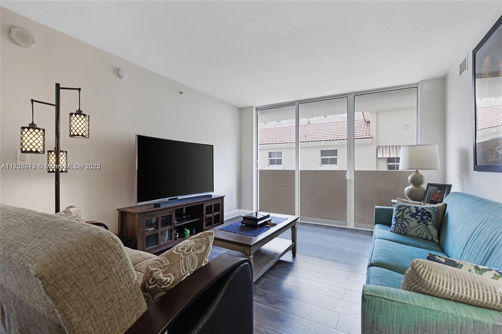 A living room features a television, a blue sofa, a coffee table, and sliding glass doors — 3232 SW 22nd Ter # 301, Miami FL 33145, MIAMI, FL