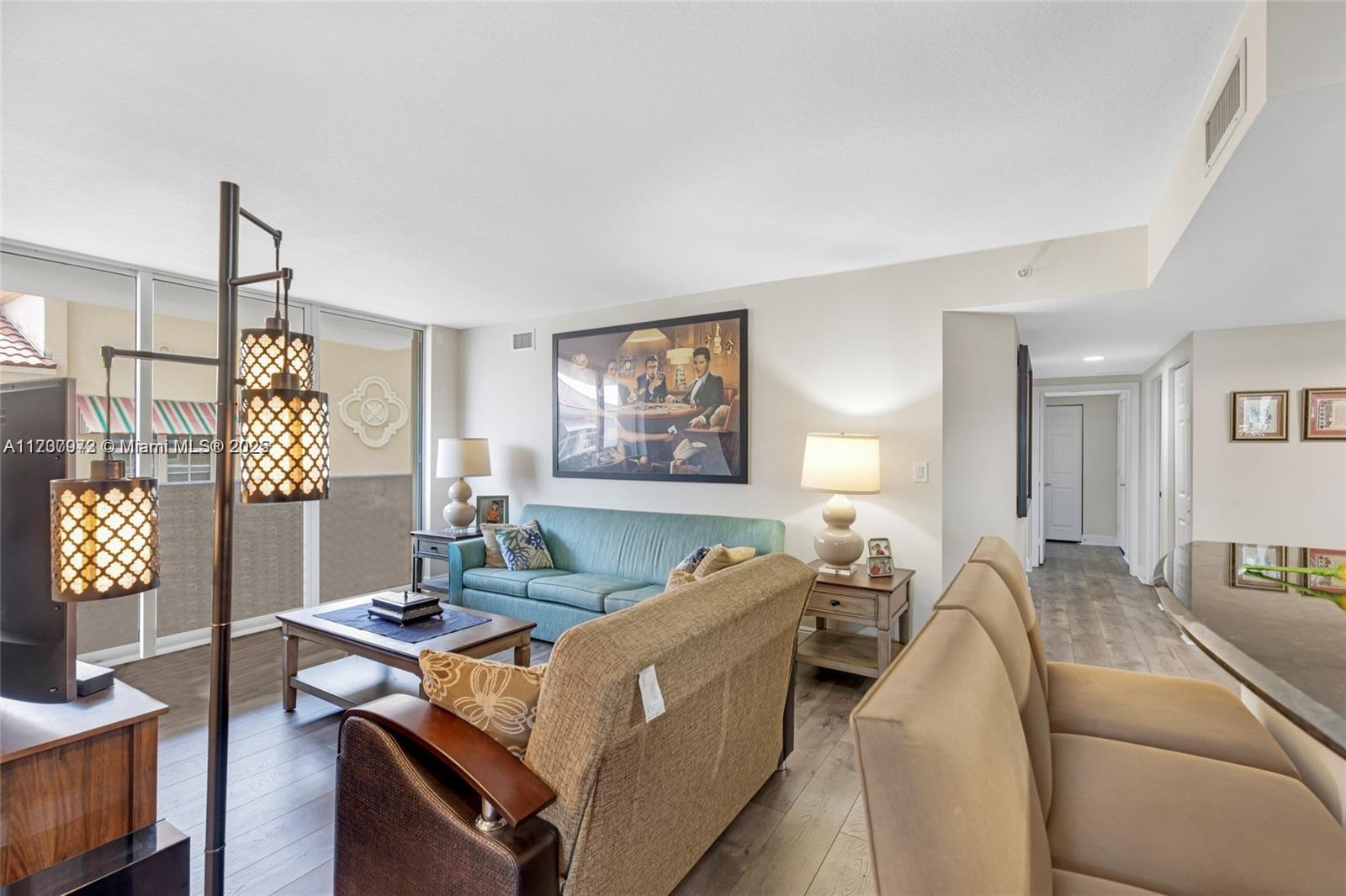 A living room features a teal sofa, a tan armchair, and a large framed wall print — 3232 SW 22nd Ter # 301, Miami FL 33145, MIAMI, FL