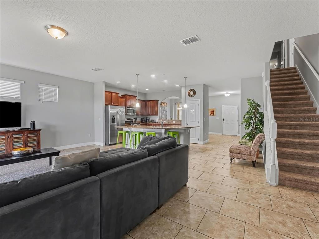 An open-concept living room and kitchen featuring a large sectional sofa and breakfast bar — 4127 OAK TREE DRIVE, DAVENPORT, FL