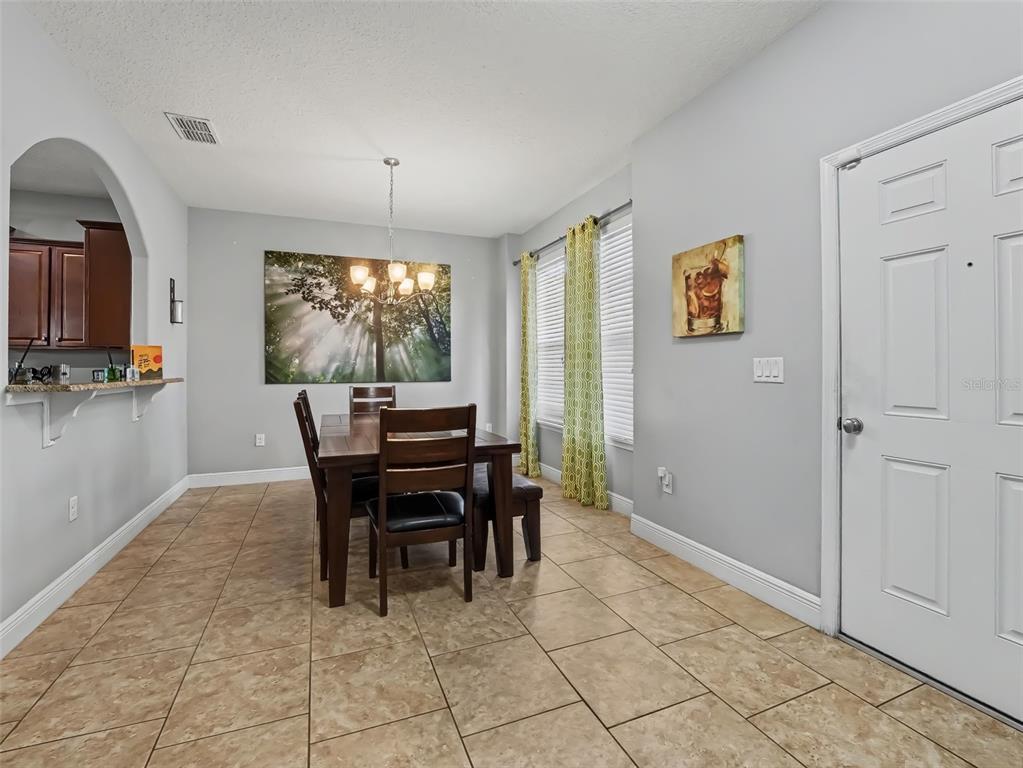 An open-concept living room and kitchen feature tile flooring, a staircase, and dark cabinetry — 4127 OAK TREE DRIVE, DAVENPORT, FL