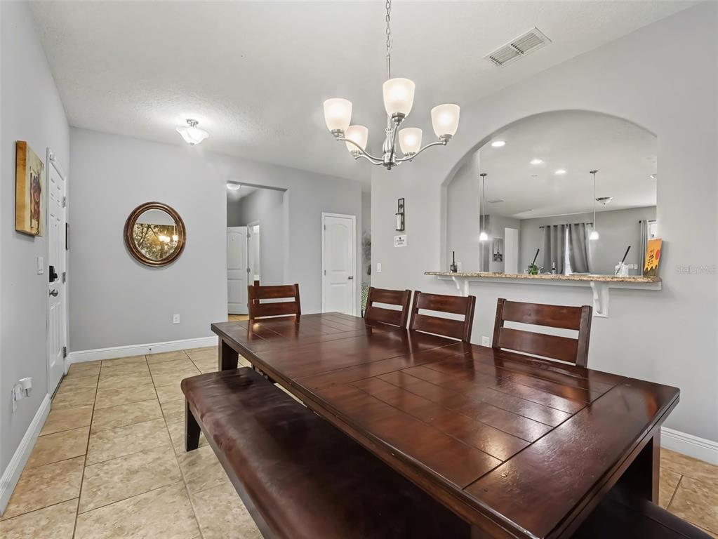 A dining room features tile flooring, a wooden table with chairs, and a large wall mural — 4127 OAK TREE DRIVE, DAVENPORT, FL