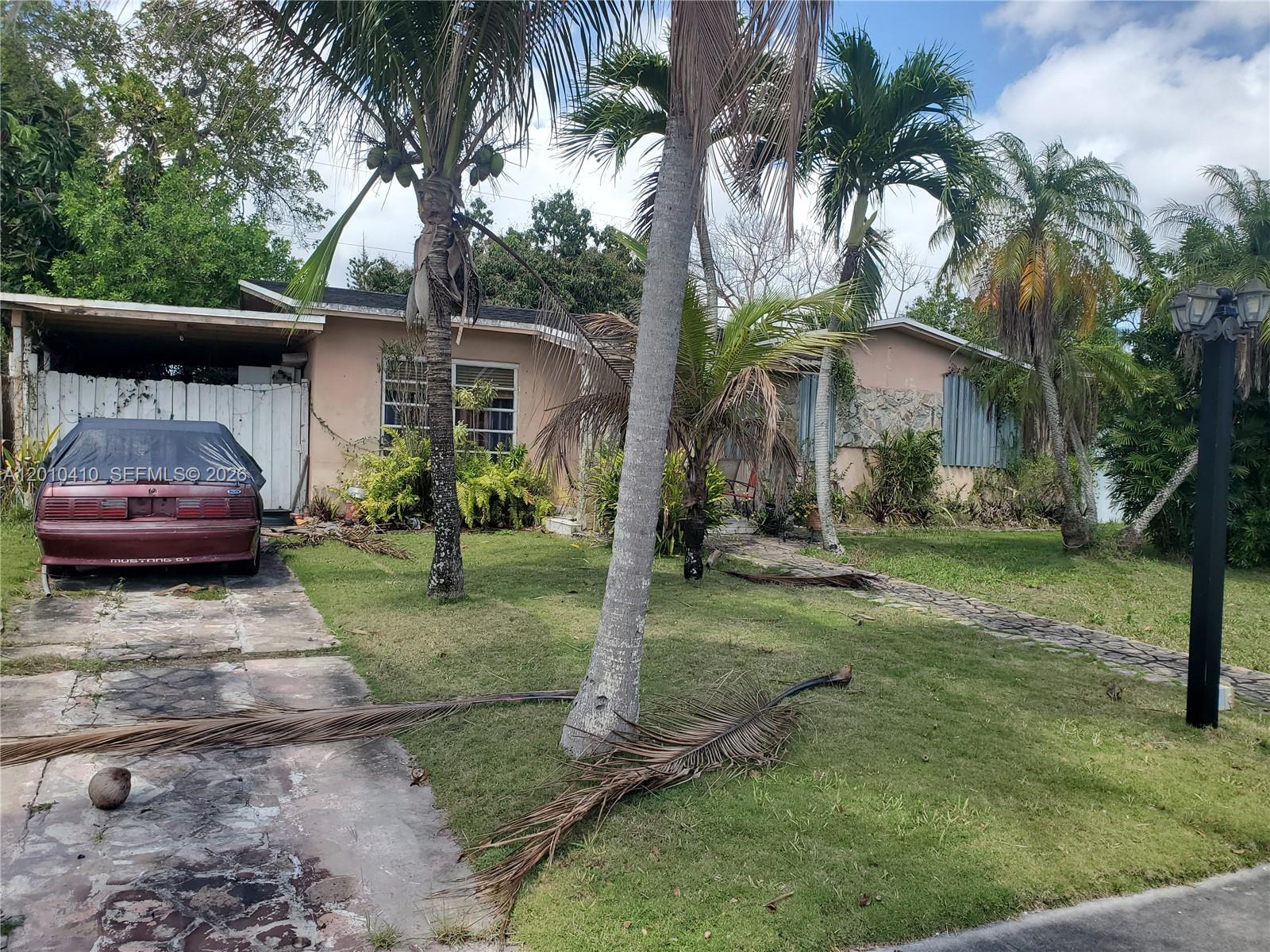 A single-story house with a carport, palm trees, and a maroon car in the driveway — 12445 SW 185th Ter, Miami FL 33177, MIAMI, FL