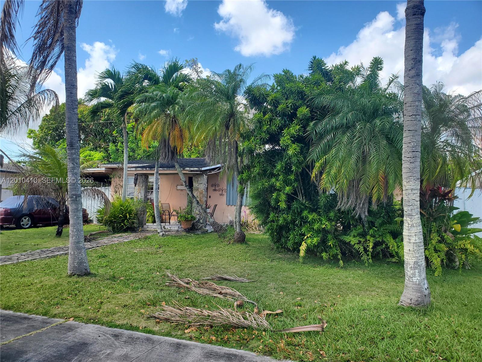 A single-story house with a stone-accented porch is surrounded by palm trees and lush landscaping — 12445 SW 185th Ter, Miami FL 33177, MIAMI, FL