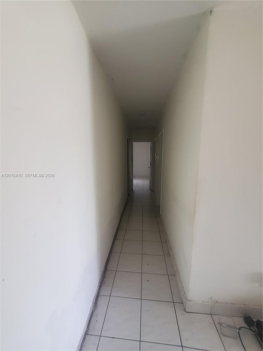 A narrow hallway features white walls and light-colored square floor tiles — 12445 SW 185th Ter, Miami FL 33177, MIAMI, FL