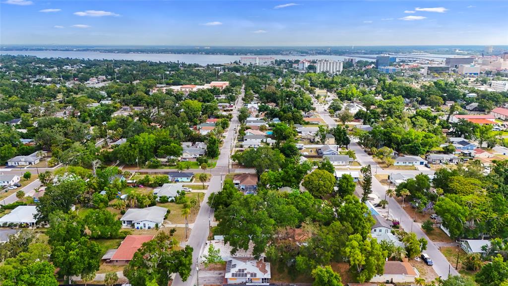 An aerial view shows a residential neighborhood with houses, lush trees, and a distant waterfront — 1419 18TH STREET W UNIT W, BRADENTON, FL