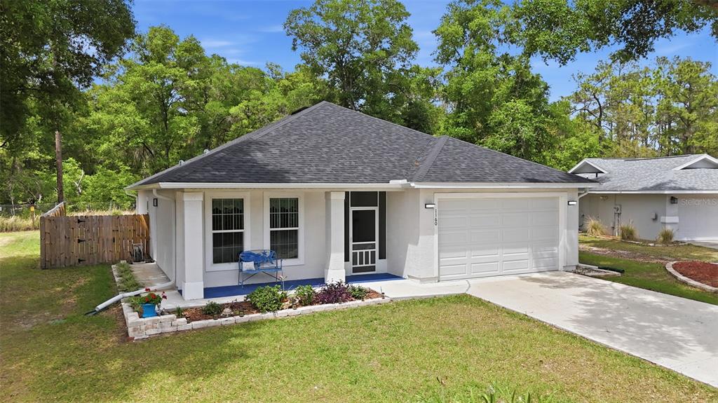 A single-story house with a white stucco exterior, dark shingled roof, and a two-car garage — 1160 NE 130TH TERRACE, SILVER SPRINGS, FL
