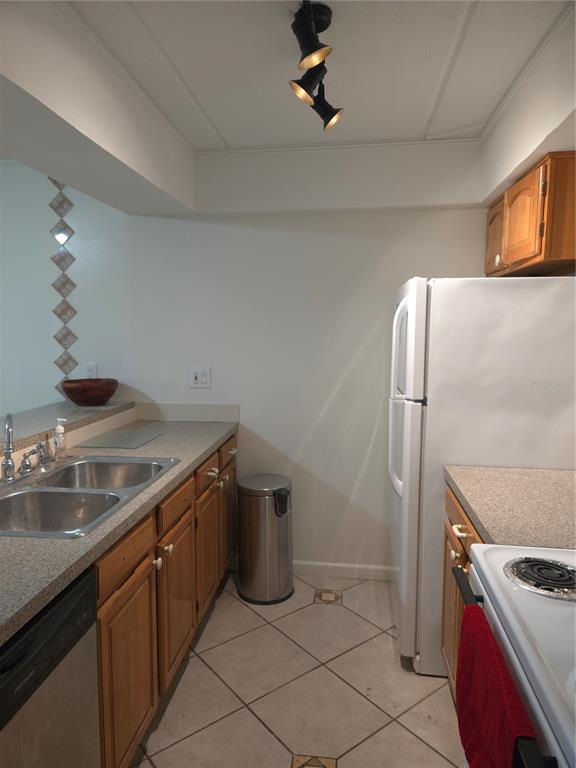 A kitchen features wood cabinets, laminate countertops, a double sink, and a white refrigerator — 12760 INDIAN ROCKS ROAD UNIT 306, LARGO, FL