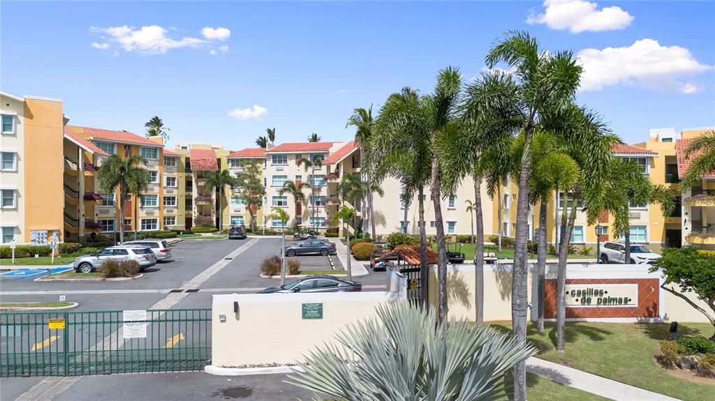 An exterior view of a multi-story apartment complex with a gated entrance and palm trees — 155 Candelero Dr. NE CANDELERO DRIVE UNIT C - 4, HUMACAO, PR