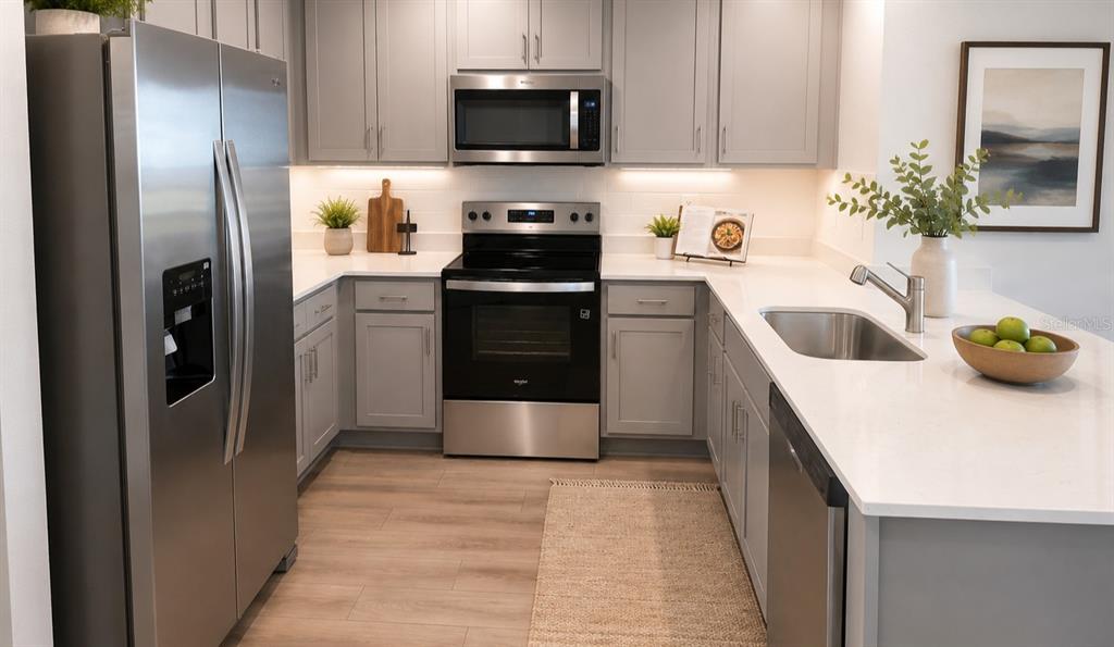 A modern kitchen features gray cabinets, stainless steel appliances, and white countertops — 230 BULL FROG LANE, UMATILLA, FL