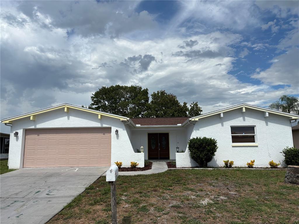A single-story white house with a two-car garage and a central front entrance — 9616 LAKE CHRISTINA LANE, PORT RICHEY, FL