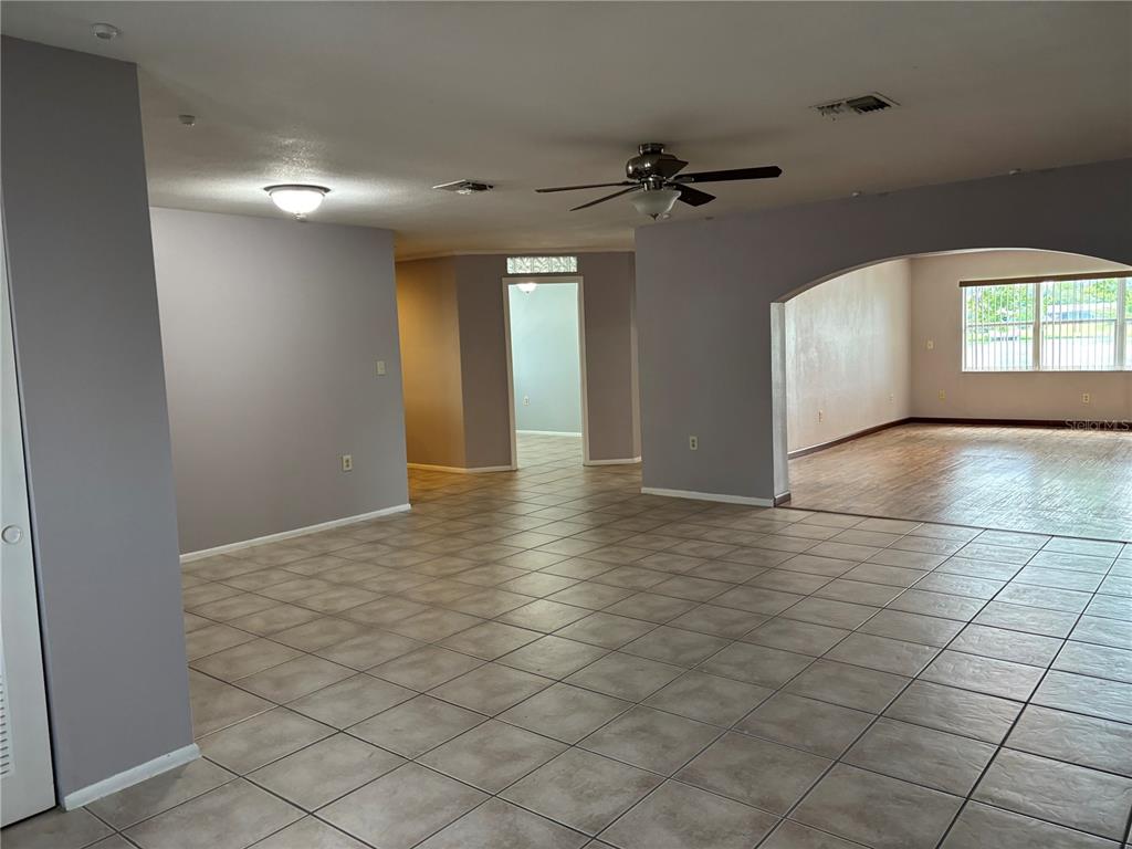 An open-concept living area features light-colored tile flooring, gray walls, and an arched entryway — 9616 LAKE CHRISTINA LANE, PORT RICHEY, FL