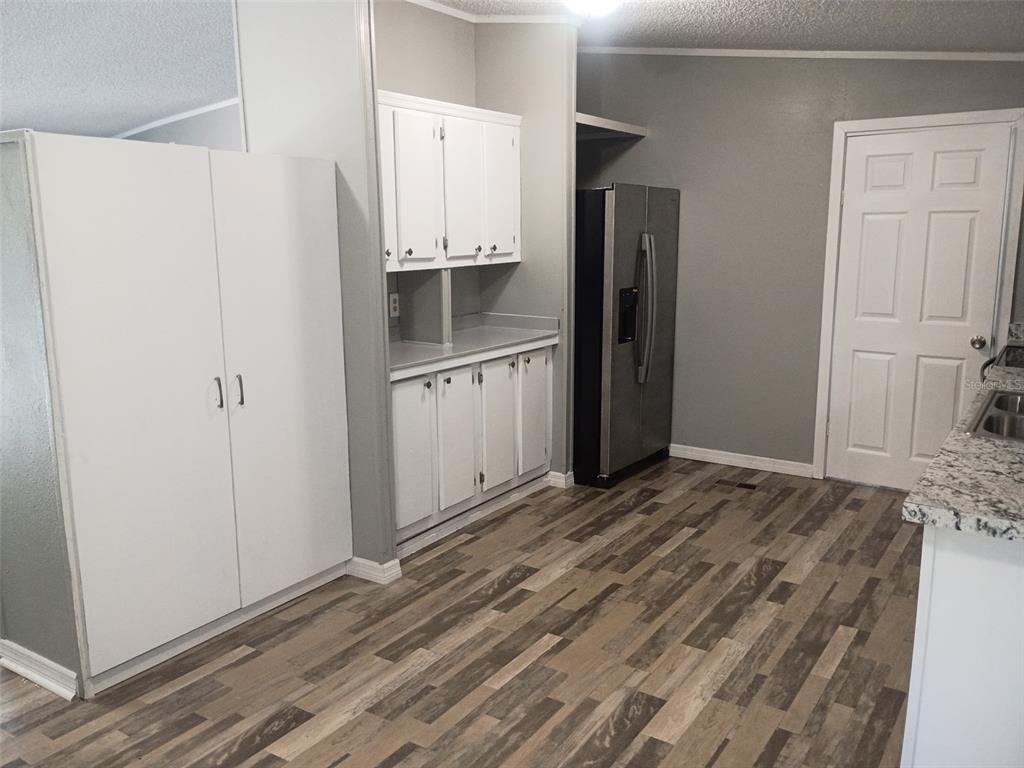 A kitchen features white cabinets, a stainless steel refrigerator, and wood-look flooring — 861 SADDLEWOOD BOULEVARD, LAKELAND, FL