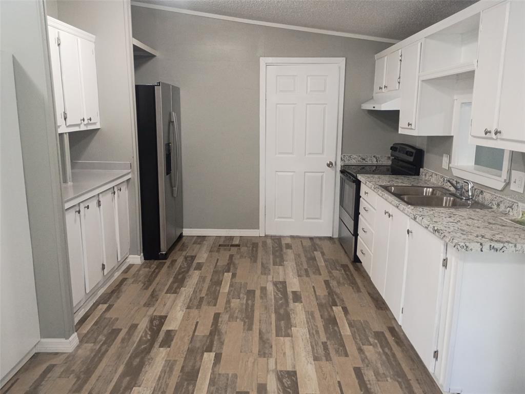 A kitchen features white cabinets, granite-look countertops, stainless steel appliances, and wood-look plank flooring — 861 SADDLEWOOD BOULEVARD, LAKELAND, FL