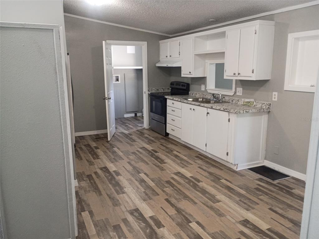 A kitchen with white cabinets, gray walls, wood-look flooring, and a stainless steel stove — 861 SADDLEWOOD BOULEVARD, LAKELAND, FL